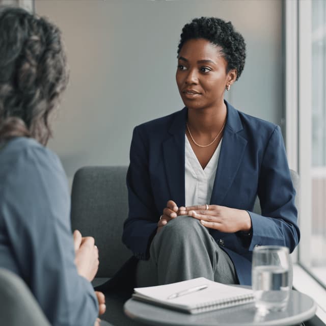 Amara Okafor speaking with a manager during a seated conversation