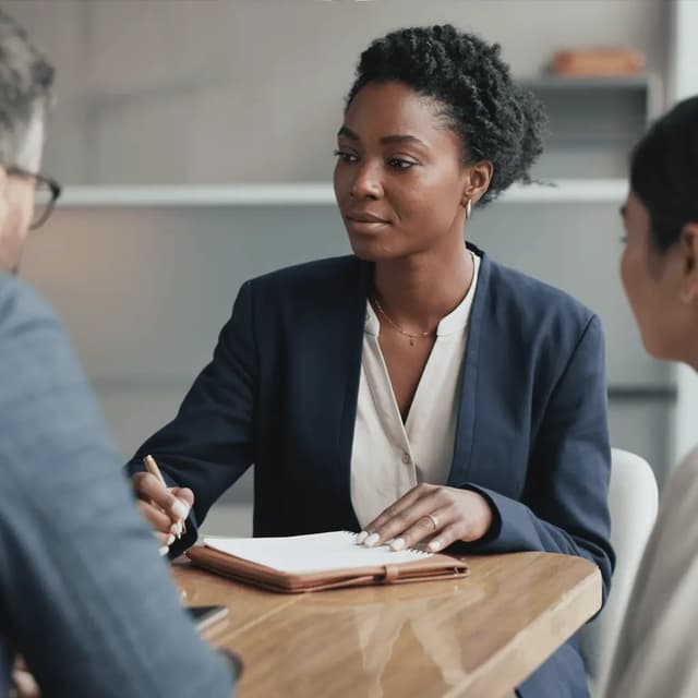 Amara Okafor seated at a meeting table with colleagues