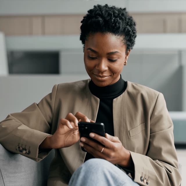 Amara Okafor looking at a phone while seated in an office
