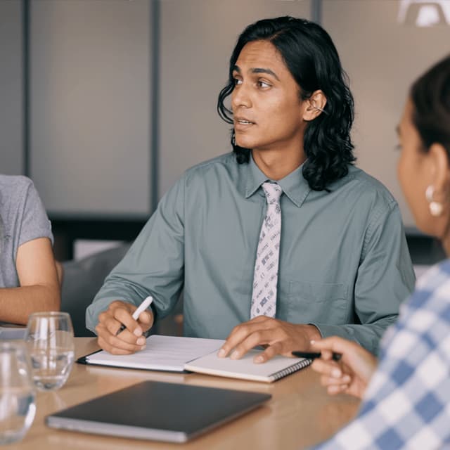 Kiran Mehta seated at a meeting table with colleagues